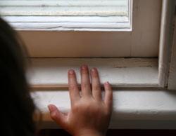 a child touching paint on a window frame