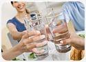 four people clinking four glasses of water
