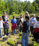 teacher demonstrating ecological restoration surrounded by kids