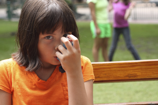 A photograph of a girl using an inhaler.