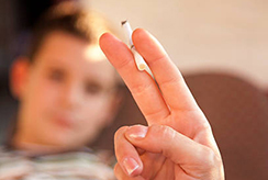 hand holding a lit cigarette near a child