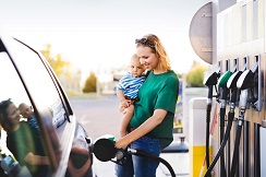 woman with toddler pumping gas