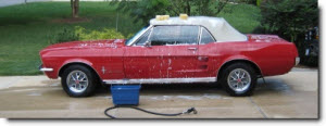 red car being washed in a driveway