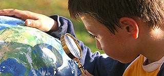 Child examining a globe with a magnifying glass