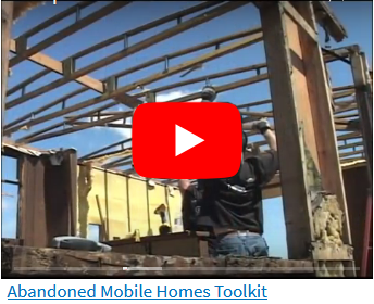 Workers deconstructing a mobile home - exposed rafters with now roof - sky visible