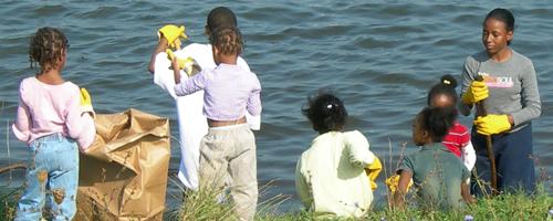 Children near a lake picking up trash