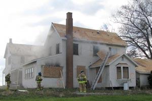 Firefighters stand outside a house being used for fire training