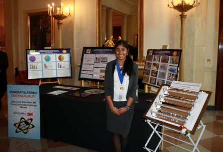 Image of Deepika Kurup next to posters of her project.