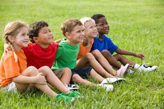 A picture of children sitting on a field of grass.