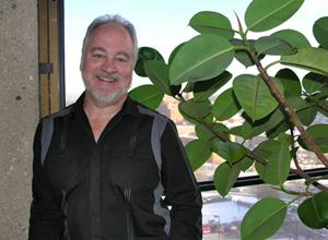 Jay Garland stands next to a plant smiling