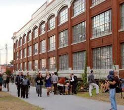 Picture of walkway full of people next to a large warehouse building