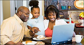 Family happily looking at a laptop screen together.