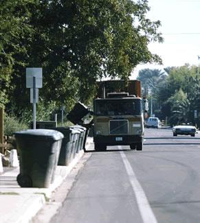 Photograph of a garbage truck driving down a city street