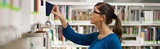 Woman looking at library shelf searching for additional information 