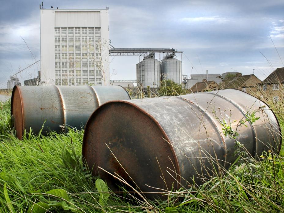 Image of rusted oil barrels at an industrial site