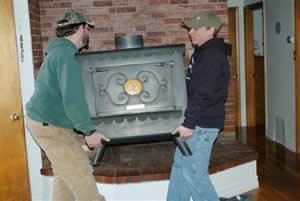Image of two men carrying a wood stove