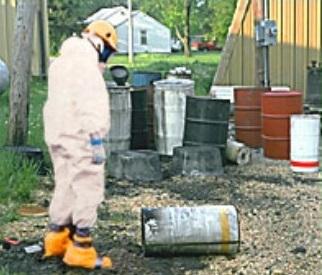 Man in hazmat suit looking at a canister