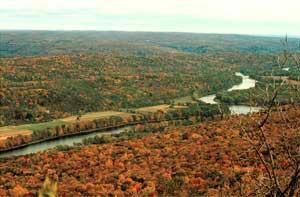 Aerial view of a river cutting through a wooded landscape.