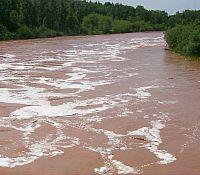 Photo showing the turbulence in a high-rising river filled with silt and sediment.