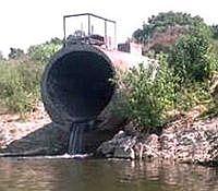 Photo of a large drain pouring into a river or stream.