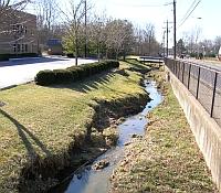 Photo showing a stream cut between two road embankments as a result of runoff.