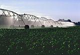 Photo of farm equipment watering/spraying large crops in a field.