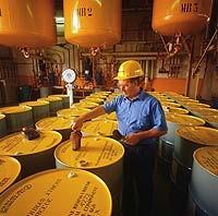 this is a picture of a man checking a yellow drum in a room full of drums