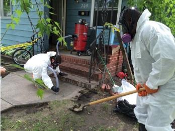 A cleanup crew removes mercury contaminated soil outside of a house.