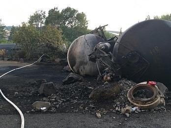 Close up photo of derailed train cars leaking crude oil.