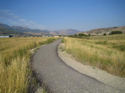 Paved walking trail through open grassy fields on the Anaconda Co Smelter site.
