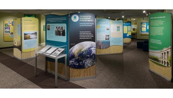 Photo of the EPA exhibit space showing informational panels. Text and photos are not legible in this photo.