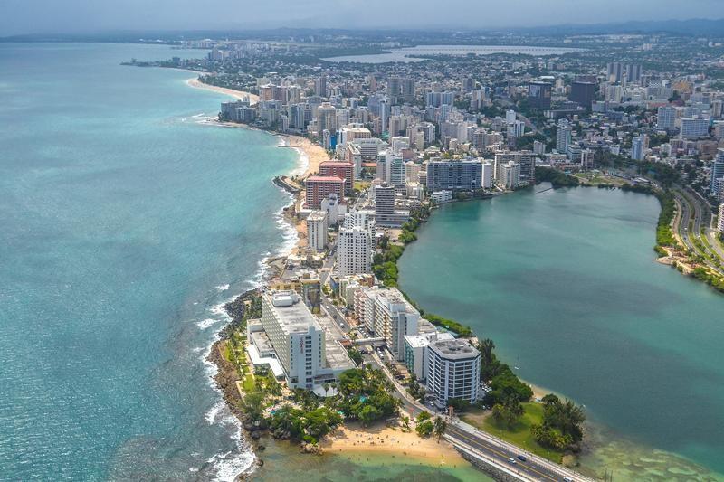 The city of san juan can be seen encircling a blue lagoon and the ocean laps on the other side