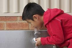 A young boy drinking from a water fountain