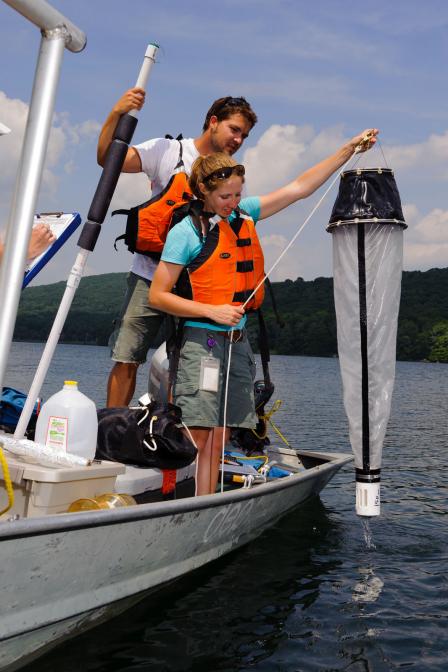 Lake researchers lower a net into the water to collect samples of zooplankton, tiny microscopic animals that drift in water. Zooplankton are biological indicators of lake water quality. 