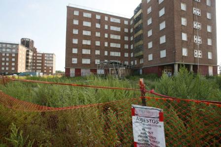 photo of pre demolished kensington towers buildings with focus on asbestos warning sign