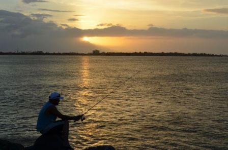 Fisherman on coast during sunset