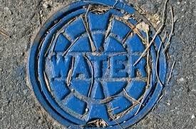A blue manhole cover with the word water stamped on it.