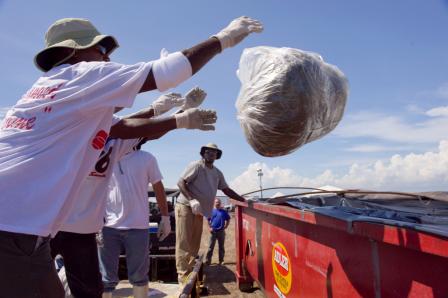 Image of men throwing bag of trash in a dumpster