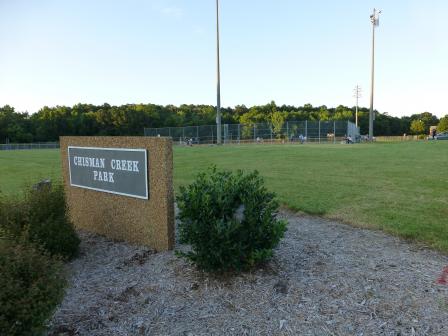 The Chisman Creek Park sign and baseball field in the background