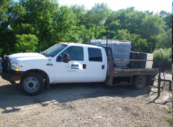 photo of company truck with clear tank of dark fluid in bed