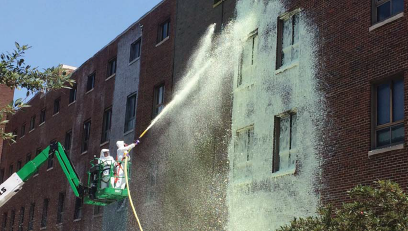 Firefighter applying a chelating agent to a building