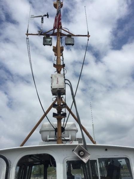 An EPA air monitor (left of the flag) sits on the mast of the NOAA research vessel.