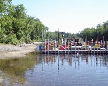 Workers on Poseidon, the submerged aquatic vegetation barge, plant vegetation as part of the post-dredging habitat reconstruction effort. Individual plants are placed down the tubes, and divers plant them into the riverbed.
