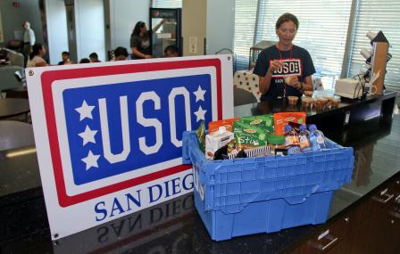 This is a picture of a donation box next to a large red, white and blue USO San Diego sign