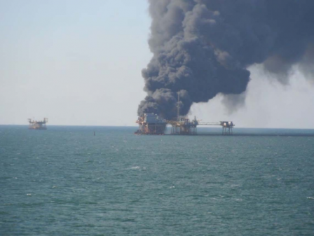 Off shore oil rig explosion with thick black smoke billowing from platform