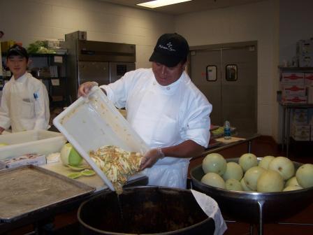 This is a picture of a kitchen worker pouring food scraps into a bin at Mohegan Sun.