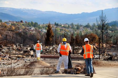 EPA work crews working in a burned out residential neighborhood wearing protective gear.