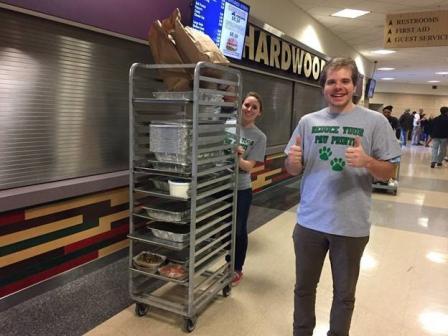 This is a picture of two University of Pittsburgh students walking with a cart of food donations.