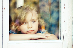 young girl in a window covered in flaky paint