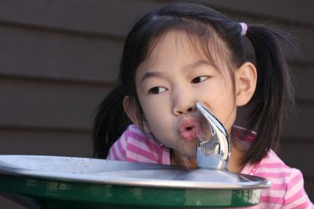 Young girl taking a drink from a water fountain
